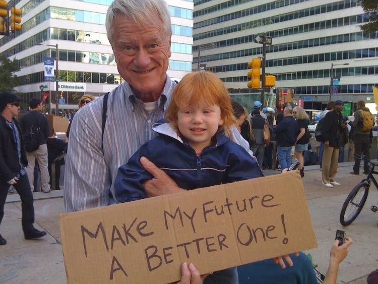 A person and child holding a sign  Description automatically generated